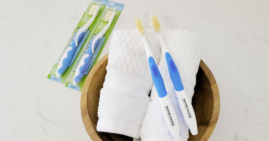 toothbrushes on towel in wood bowl