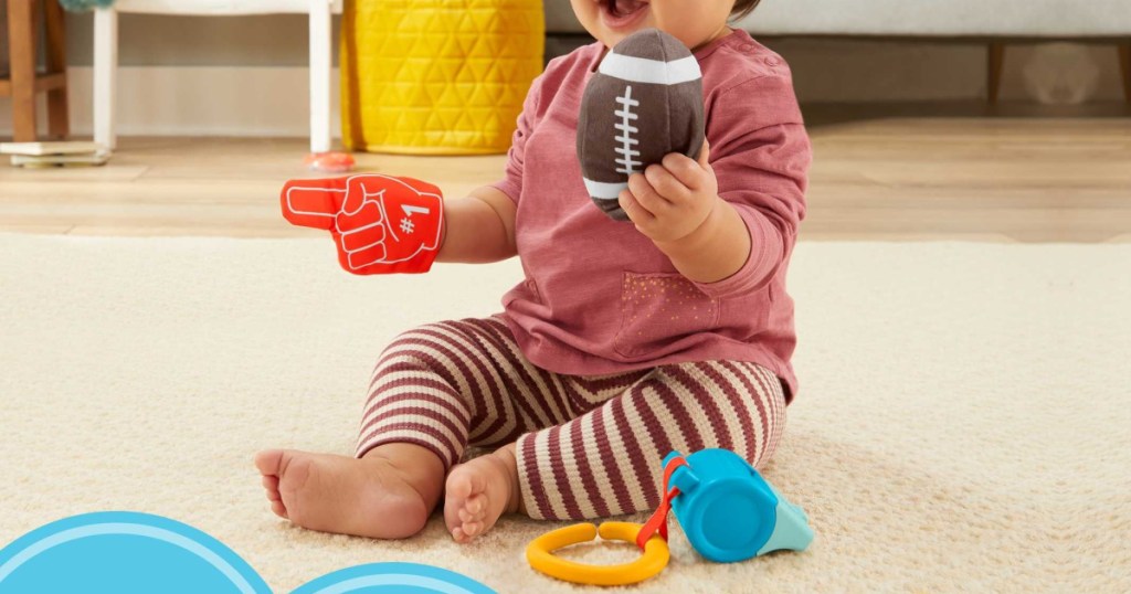 baby girl playing with three football themed toys