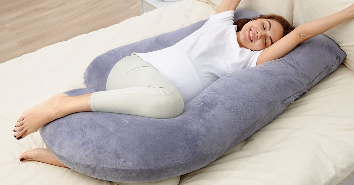 woman laying on bed with u-shaped body pillow