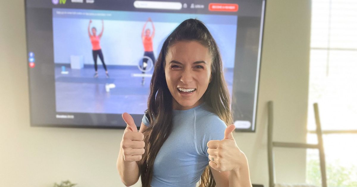 a girl doing Get Healthy U TV at home workouts in front of a flatscreen tv on the wall