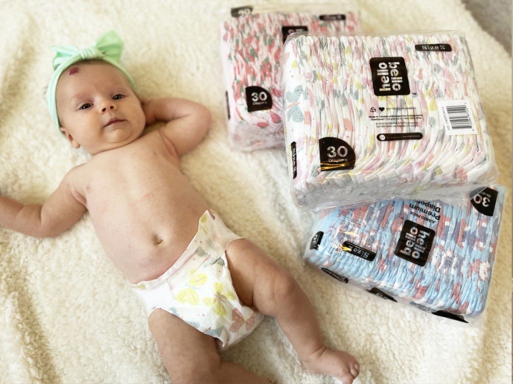 baby laying next to packs of hello bello diapers