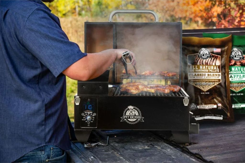 Pit Boss Copper Series Table Top Wood Pellet Grill shown in use outdoors with a man grilling