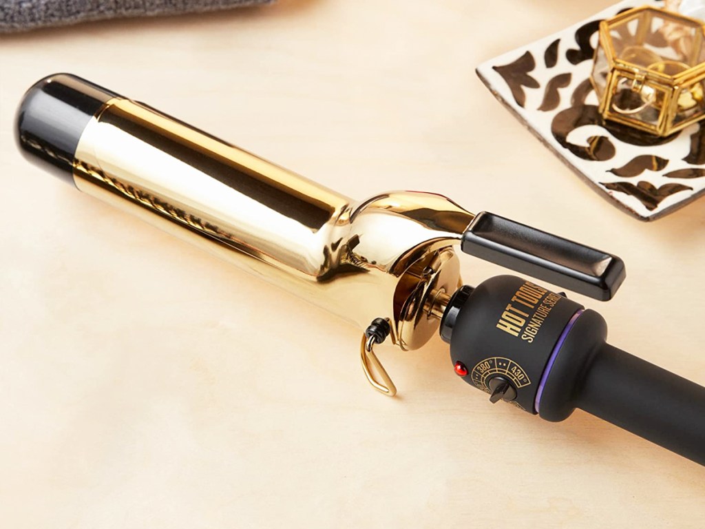 black and gold curling wand next to hair clip