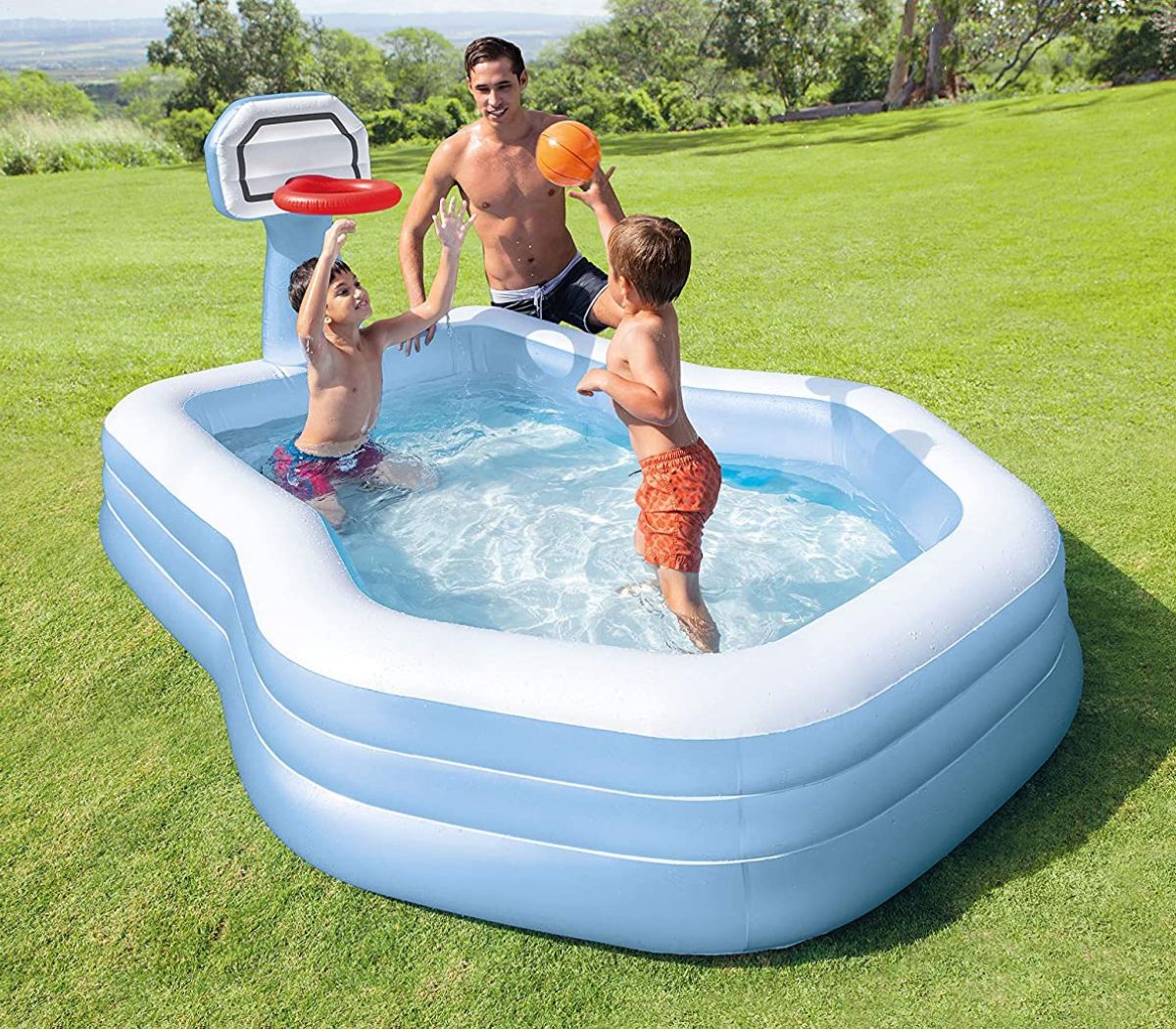 A dad and two sons shooting hoops in inflatable basketball themed pool