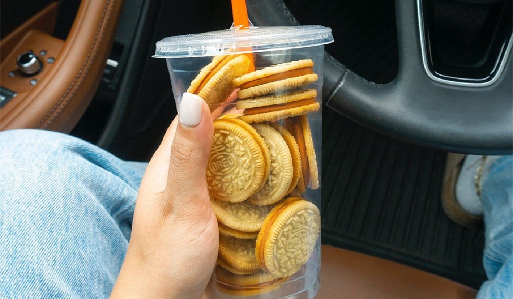 hand holding pumpkin spice OREO cookies in plastic cup