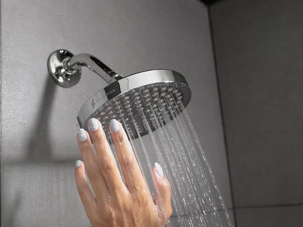 hand reaching to shower head spraying water down