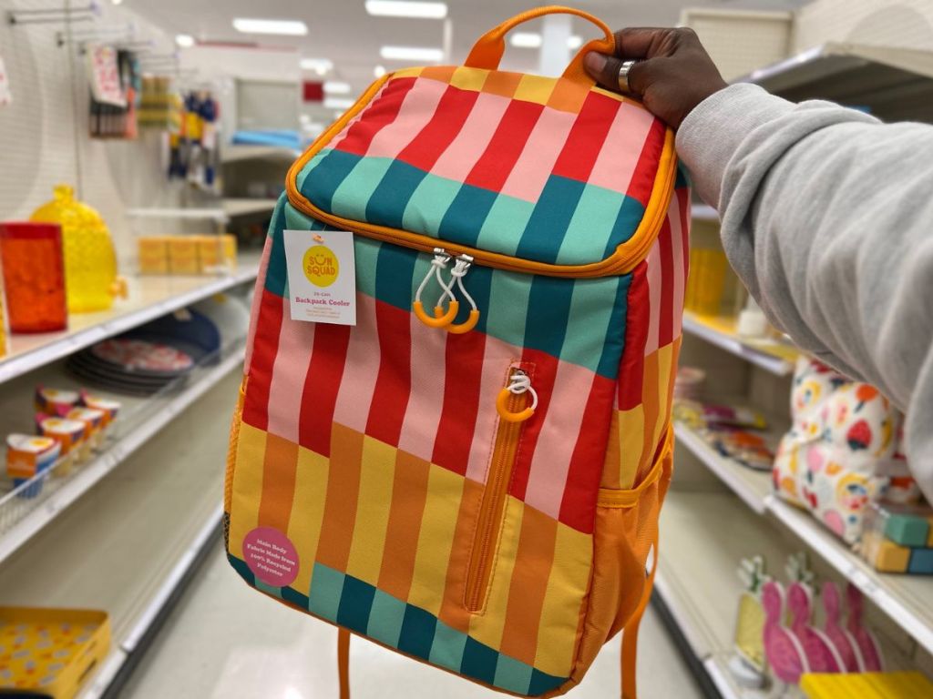 Hand holding a striped Sun Squad Cooler Backpack.