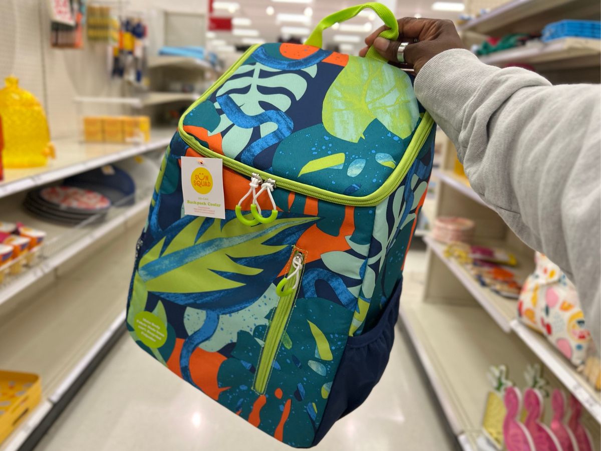 Hand holding a Sun Squad Cooler Backpack in jungle print