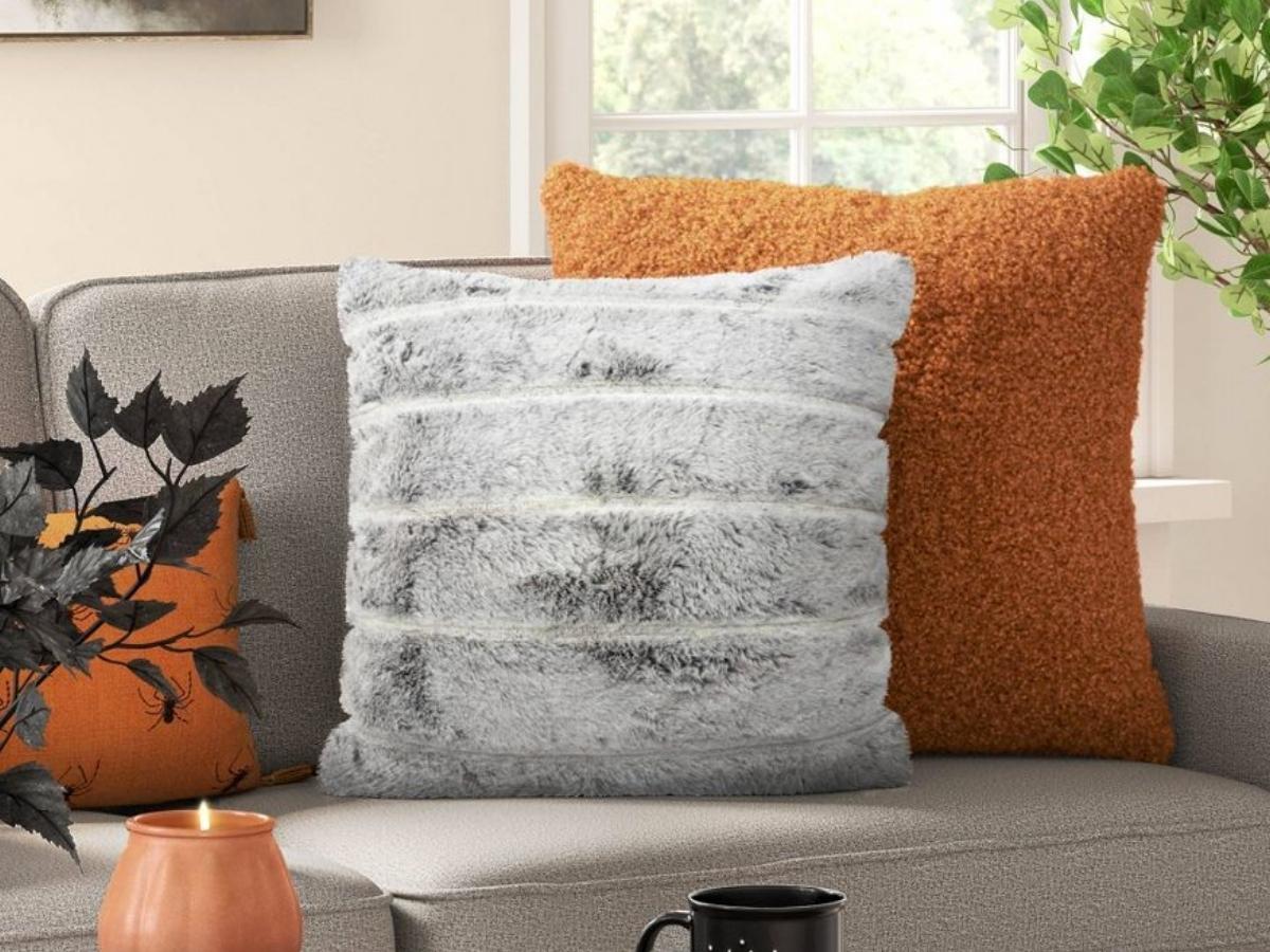 Gray Faux Fur Square Pillow leaning on burnt orange pillow on gray couch