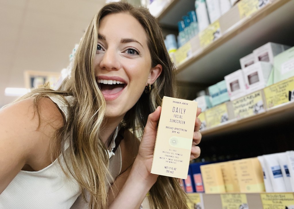 woman holding trader joes daily facial sunscreen in store