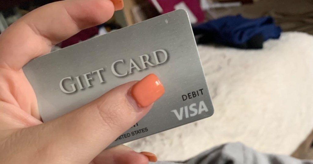 woman with pink nails holding visa gift card