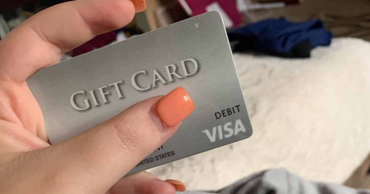 woman with pink nails holding visa gift card