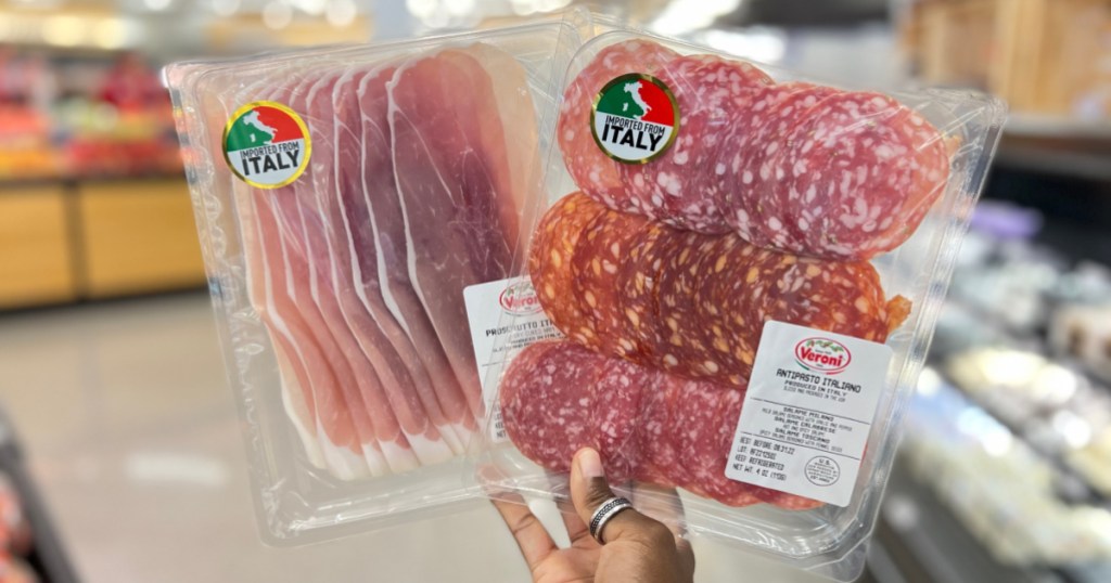 hand holding two packages of pre-sliced meats in store