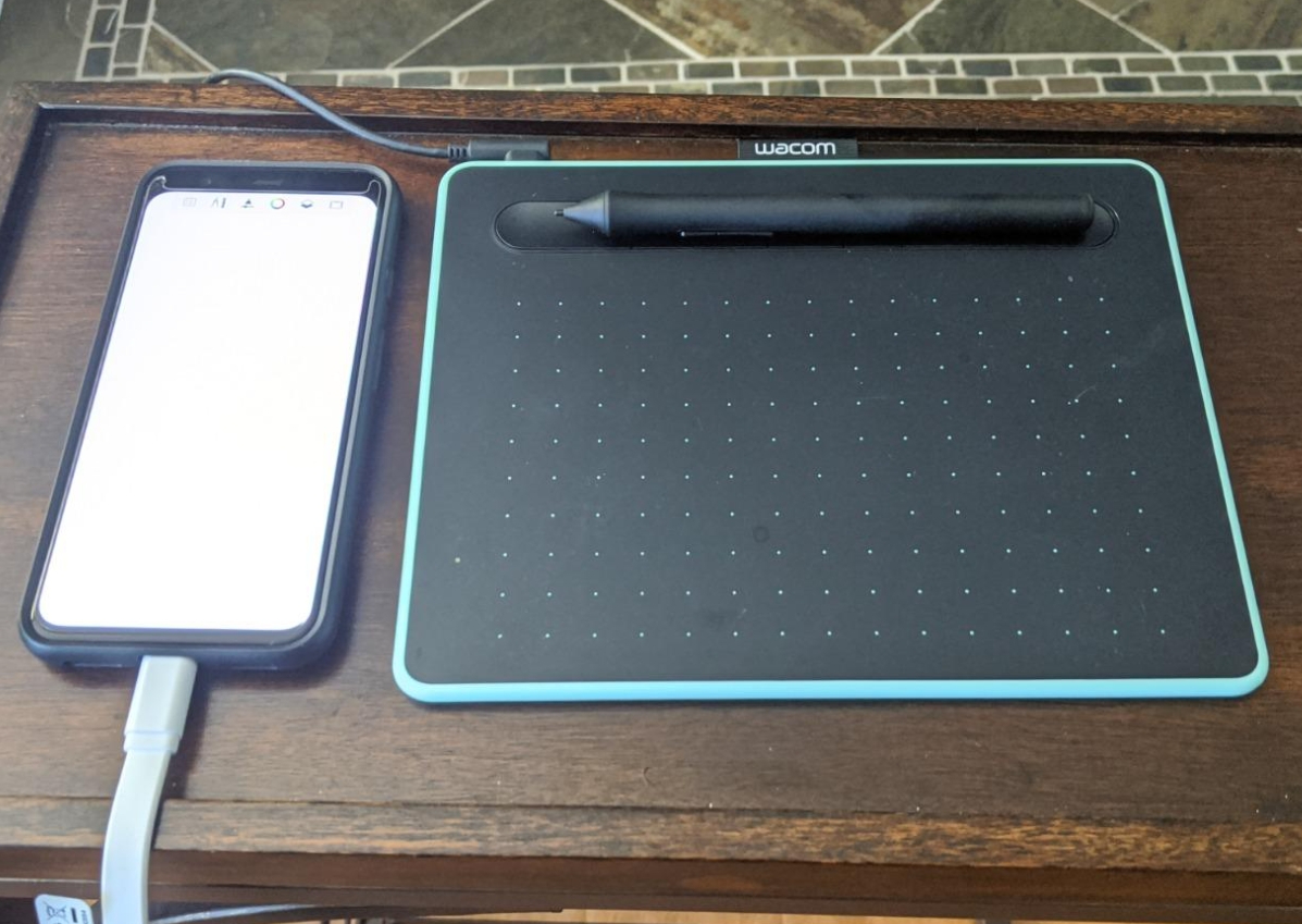 Wacom Tablet with Stylus laying next to a phone with a blank screen