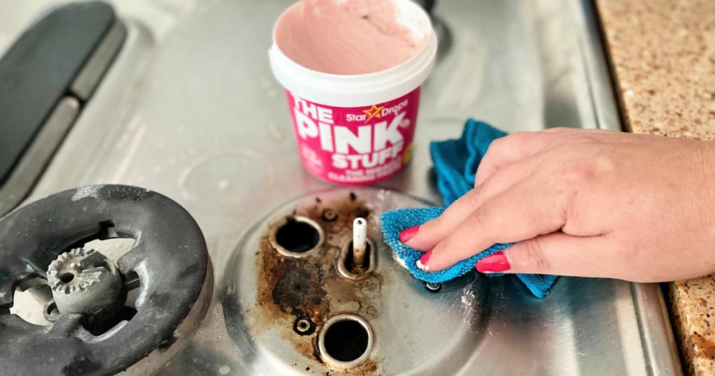 Woman cleaning stove with Pink Stuff