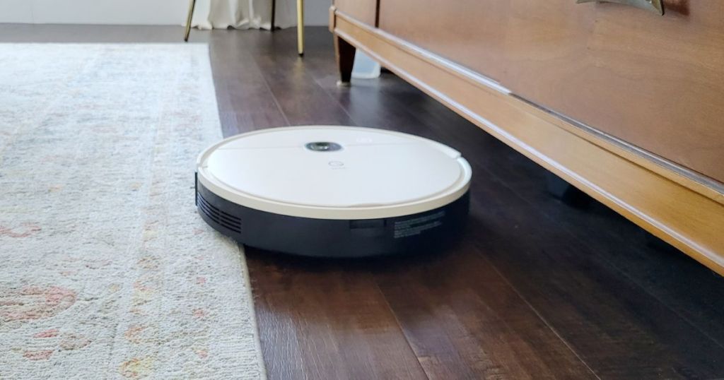Yeedi Robot Vacuum on hardwood floor next to an area rug and dresser