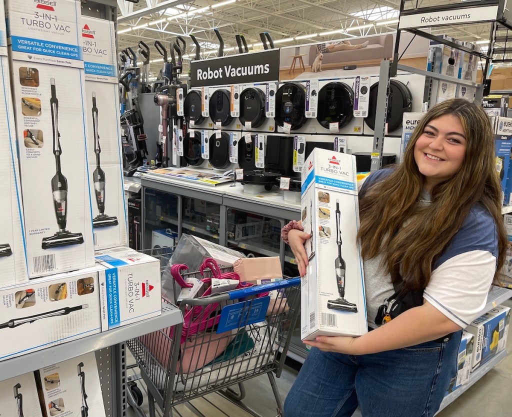woman holding bissell stick vacuum in walmart store aisle