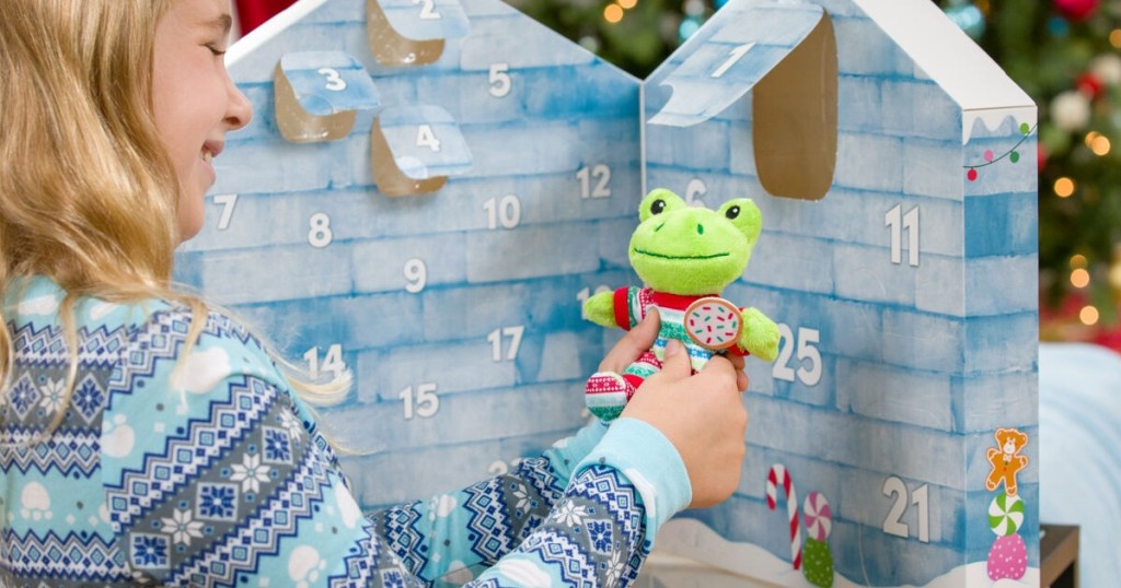 girl removing plus frog from Advent calendar