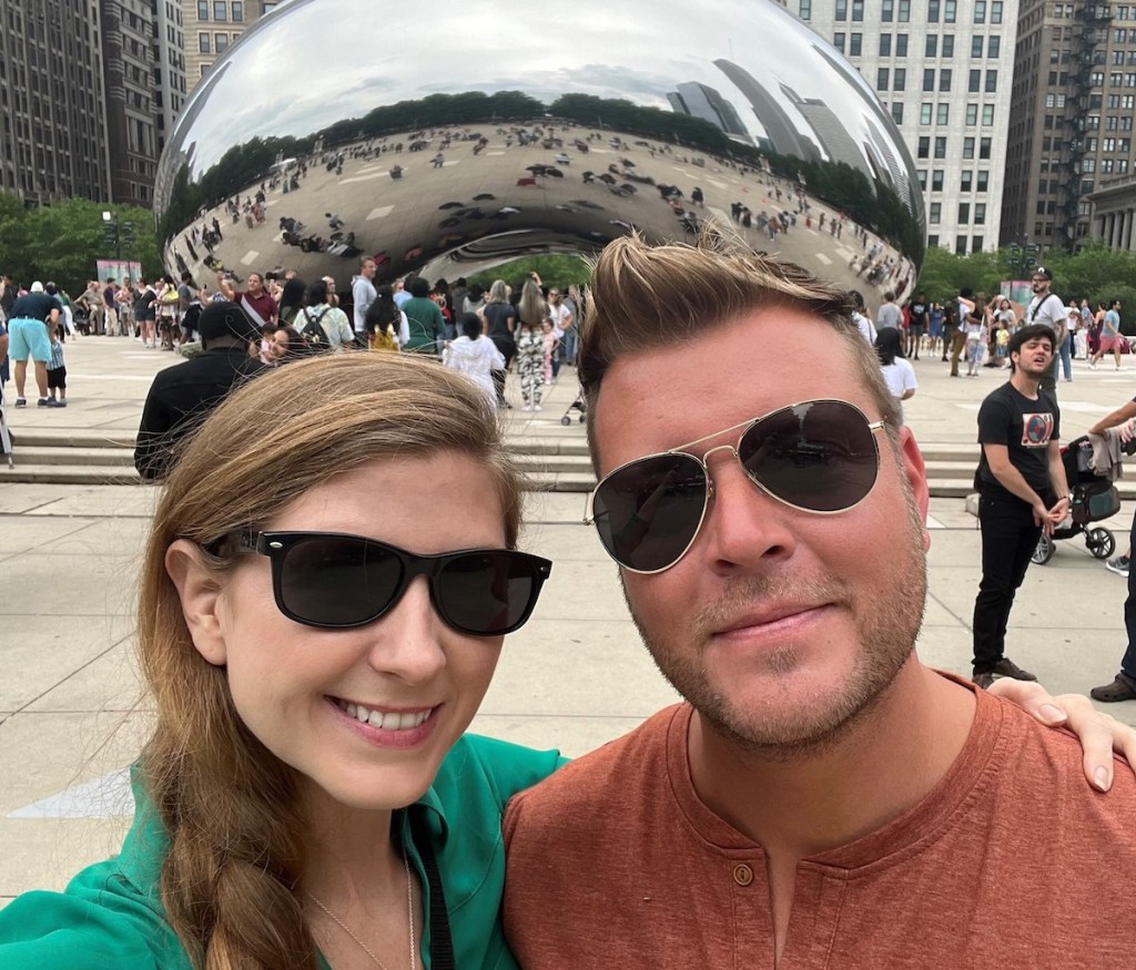 woman and man standing in front of silver bean cloud gate sculpture in chicago