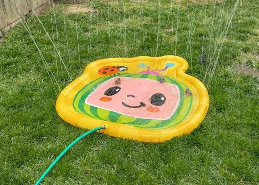 a cocomelon splash pad connected to a waterhose in a back yard