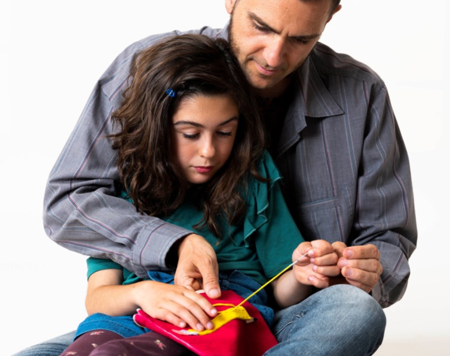man and girl sewing a craft together