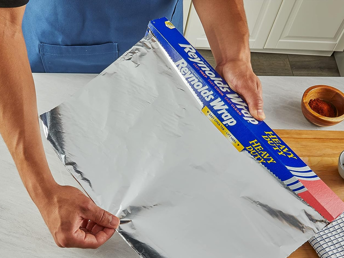 https://hip2save.com/wp-content/uploads/2022/07/hand-pulling-Reynolds-wrap-aluminum-foil-to-wrap-left-overs.jpg