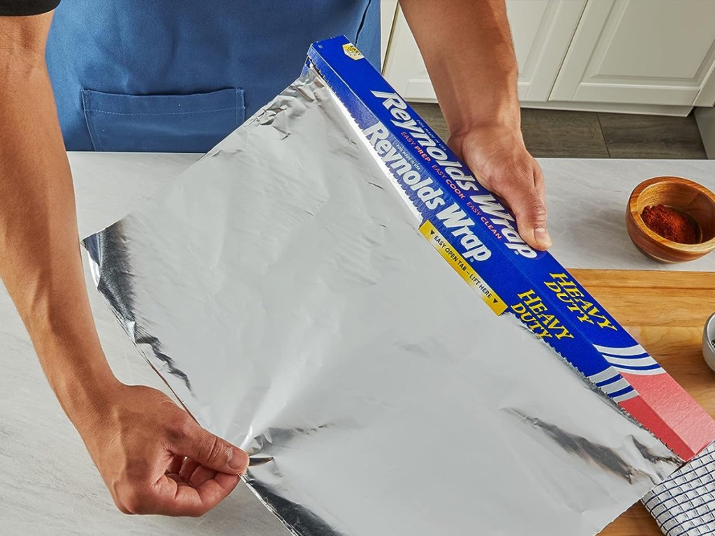 hand-pulling-Reynolds-wrap-aluminum-foil-to-wrap-left-overs تغليف رينولدز بورق الألمنيوم 75 قدم مربع.  قدم.  فقط 3.78 دولار على أمازون (11 دولارًا قياسيًا)