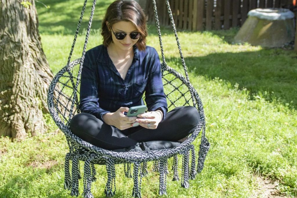 woman sitting in gray hammock chair outside