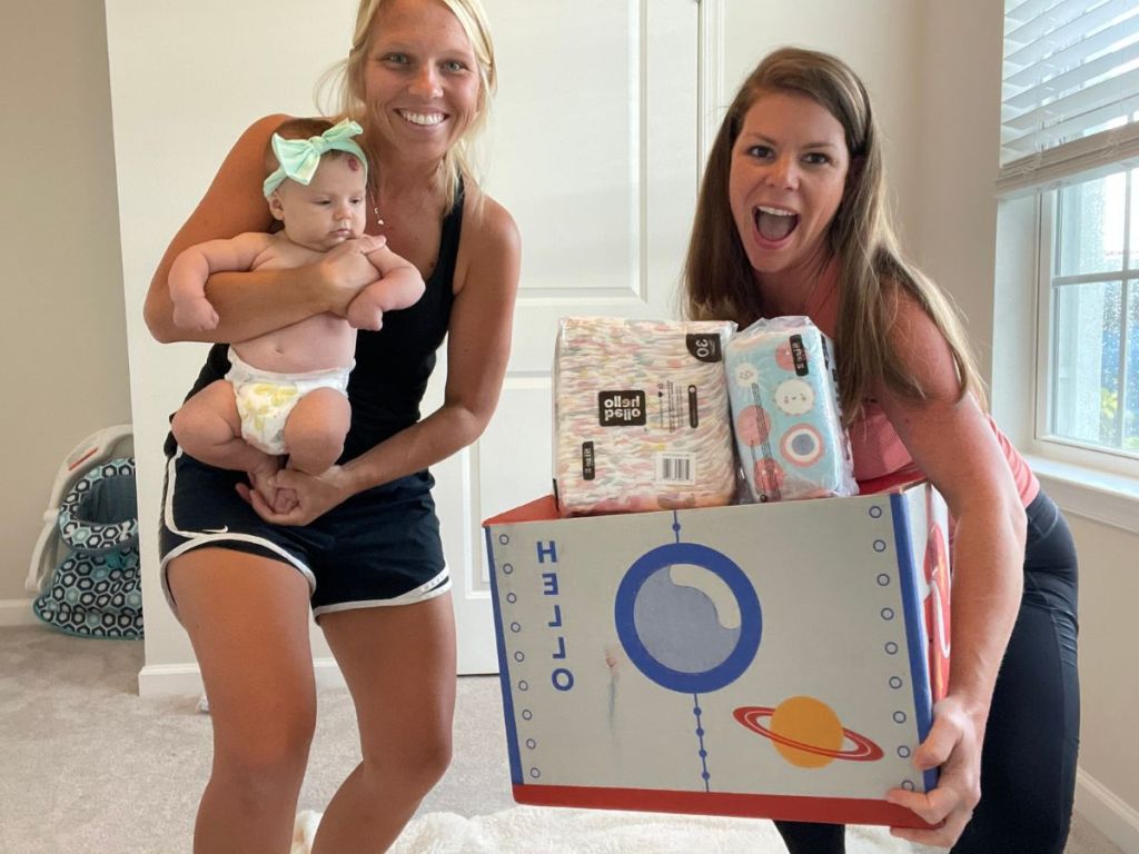 woman holding baby and woman holding Hello Bello box of diapers