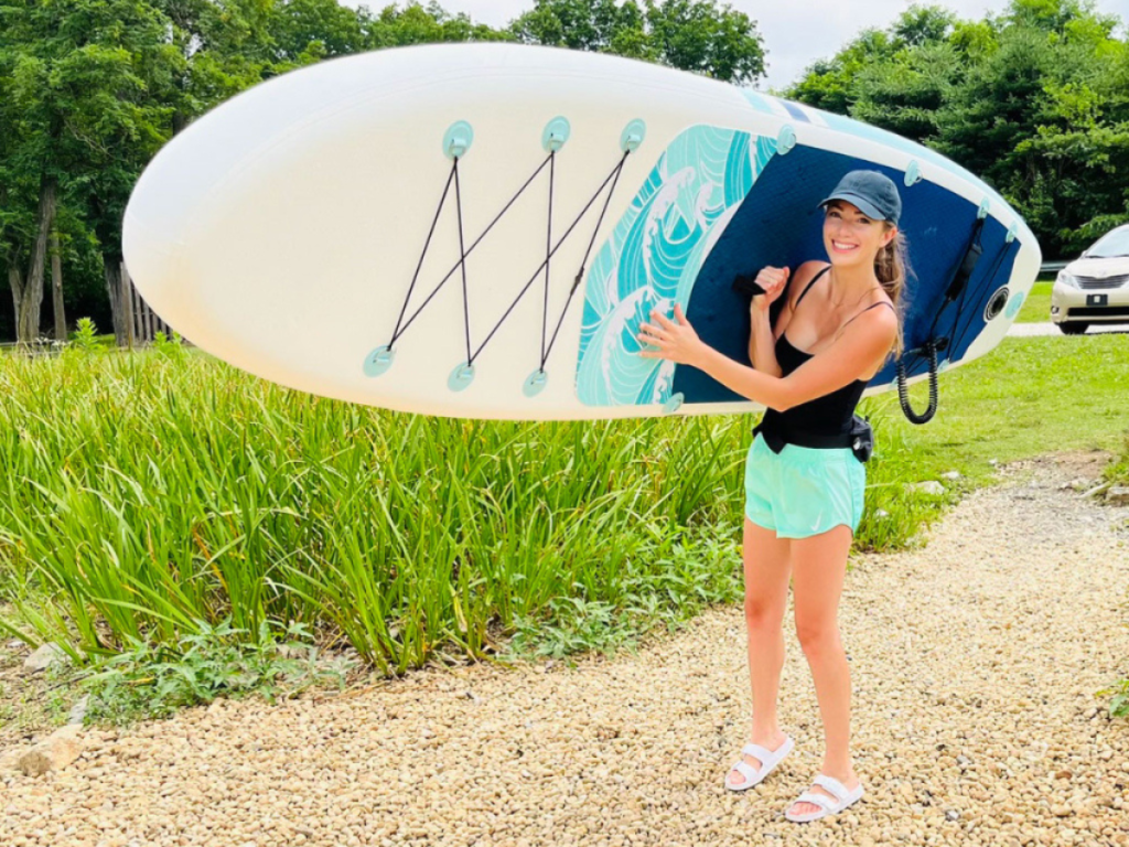 woman carrying an inflatable paddle board