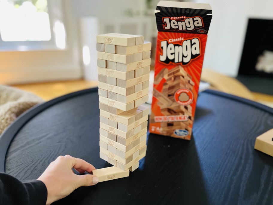 hand pulling bottom of jenga block off tower