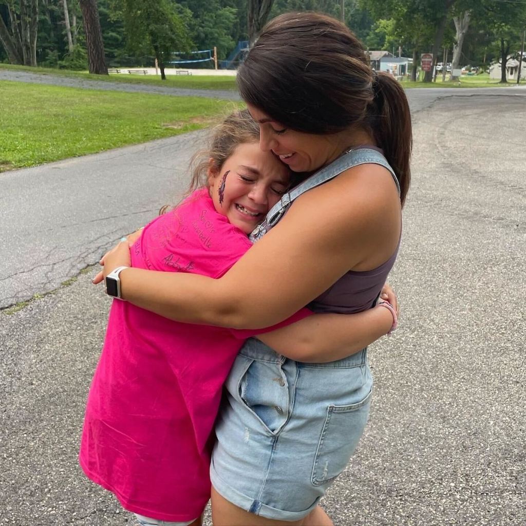 woman and girl in bright pink shirt hugging and crying happy tears