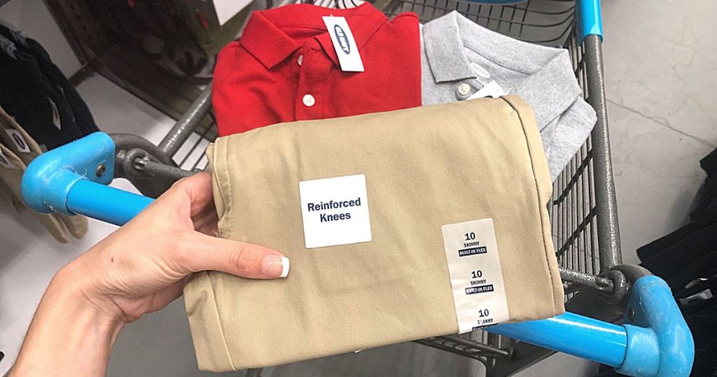 hand holding Old Navy uniform pants with uniform polos in cart 