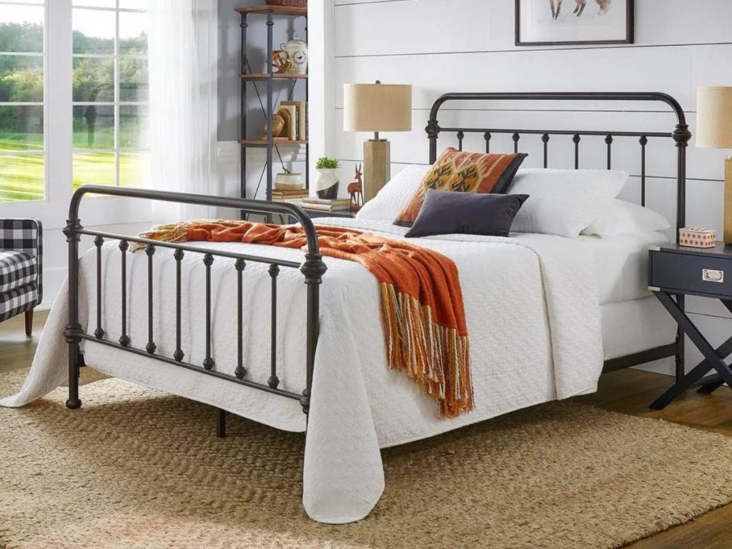 iron frame bed with white linens and rust-colored accents