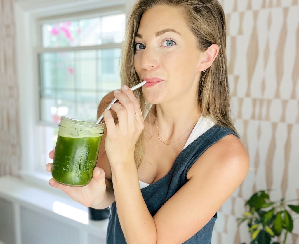woman sipping green drink from silver metal straw 