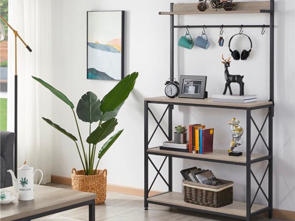 metal and wood kitchen shelf with coffee mugs and headphones hanging on hooks and shelves have decor and books on display