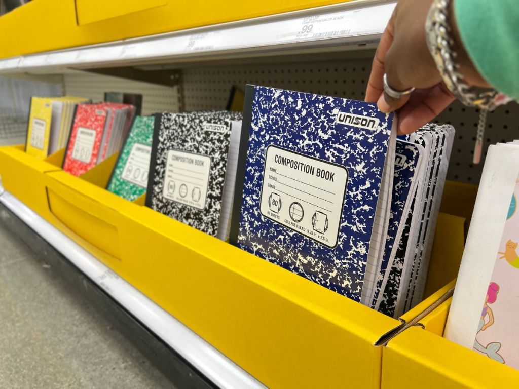 person grabbing Composition Notebook from shelf in store