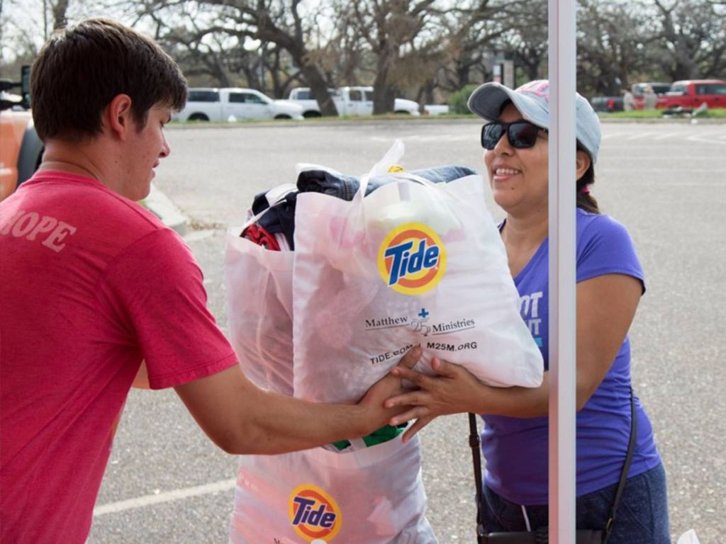 man handing Tide tote bag filled with donations to lady
