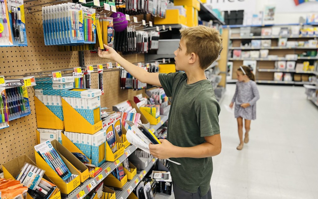 boy standing in walmart store aisle picking out school supplies