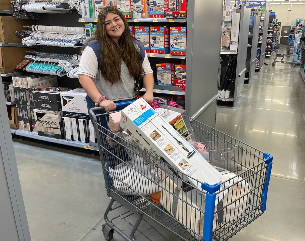 woman standing with walmart shopping cart filled with dorm room essentials