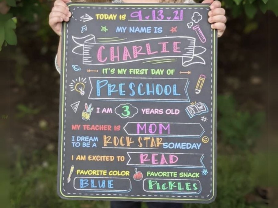 little girl holding a first day of school chalkboard sign
