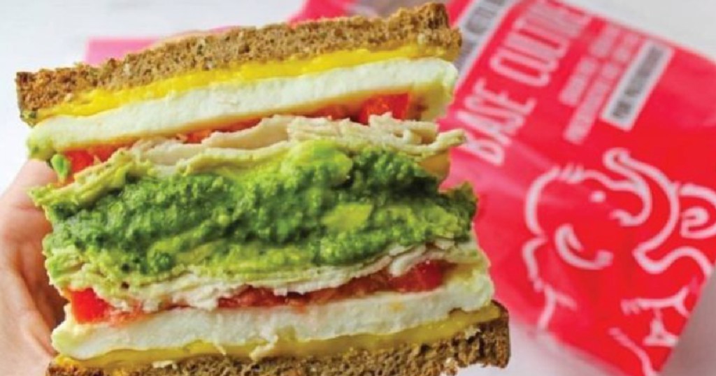 hand holding sandwich with avocado and egg 