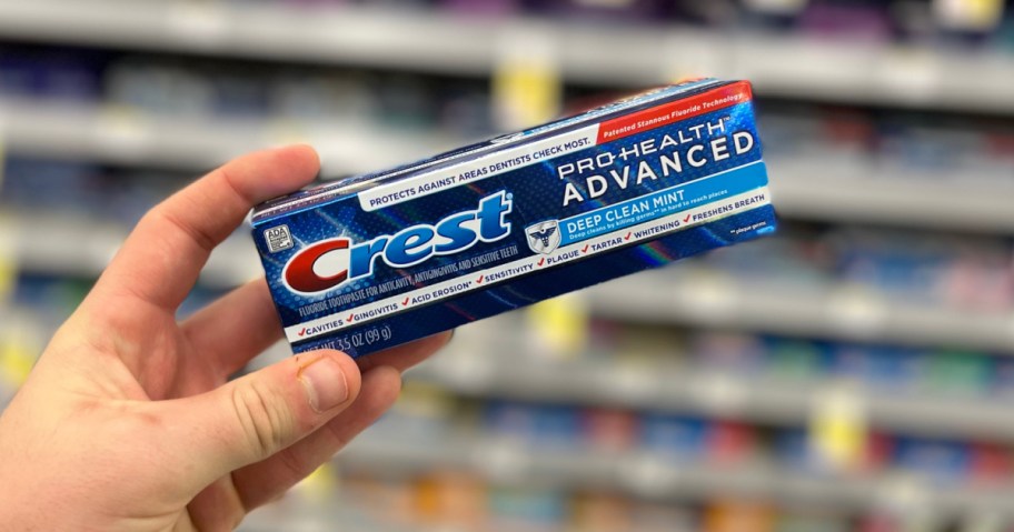 man holding up Crest Pro Health Toothpaste inside Walgreens store