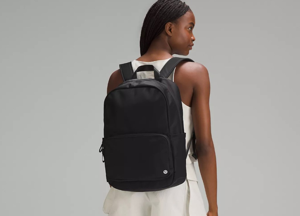 woman wearing black backpack standing in gray room