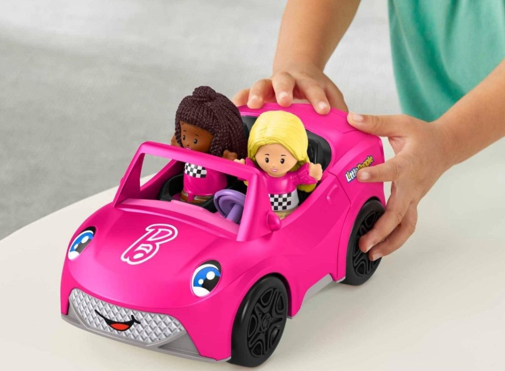 girl playing with a Fisher-Price Little People Barbie Convertible Vehicle