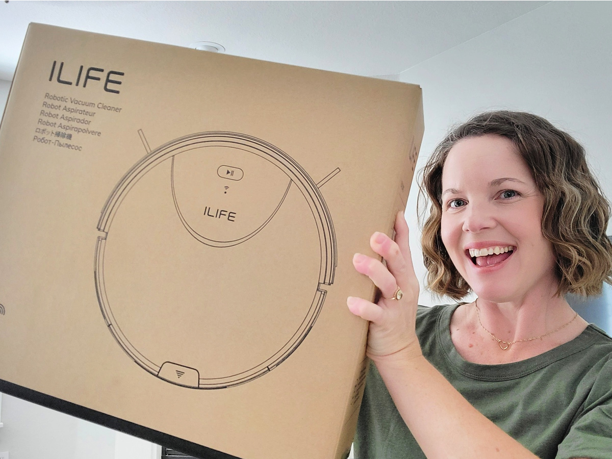 woman holding up an ILIFE Robot Vacuum box