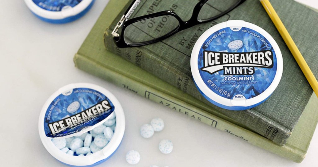 small tins of mints on desk with books and glasses