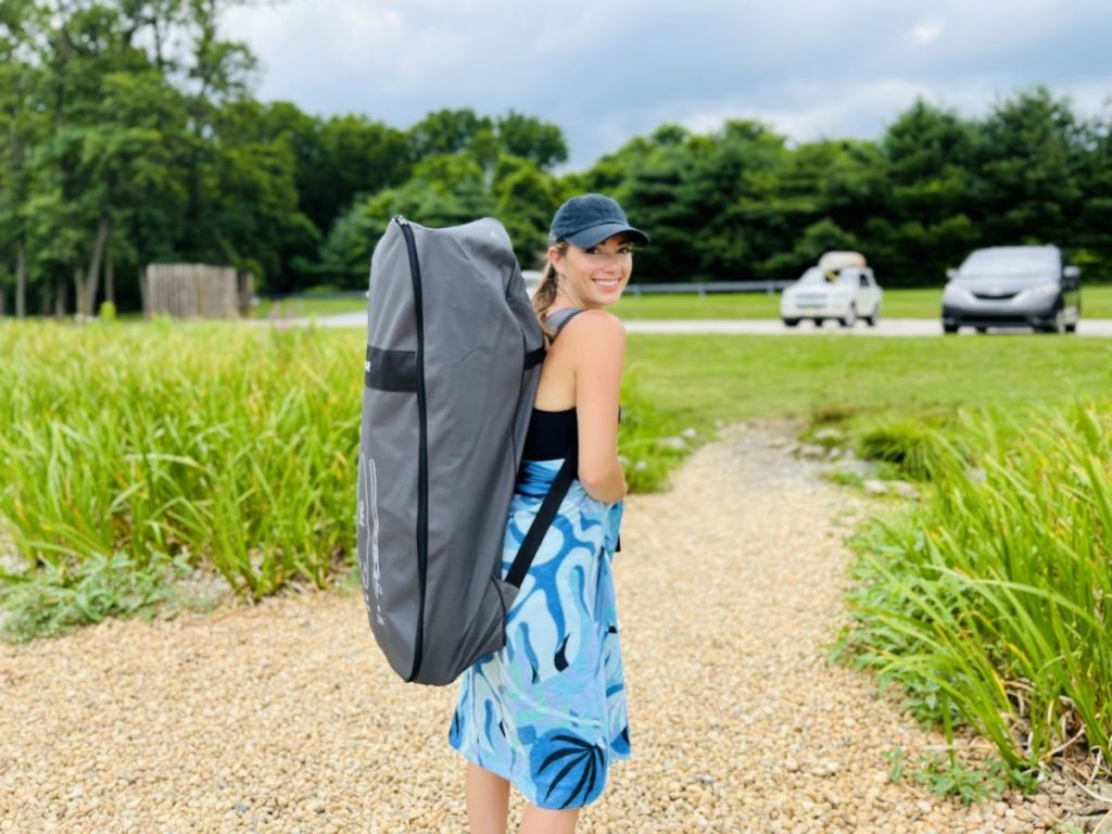 woman carrying a bag with an inflatable paddleboard