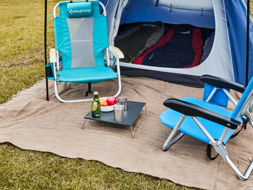 outdoor blanket, camping chairs, and tent set up outside