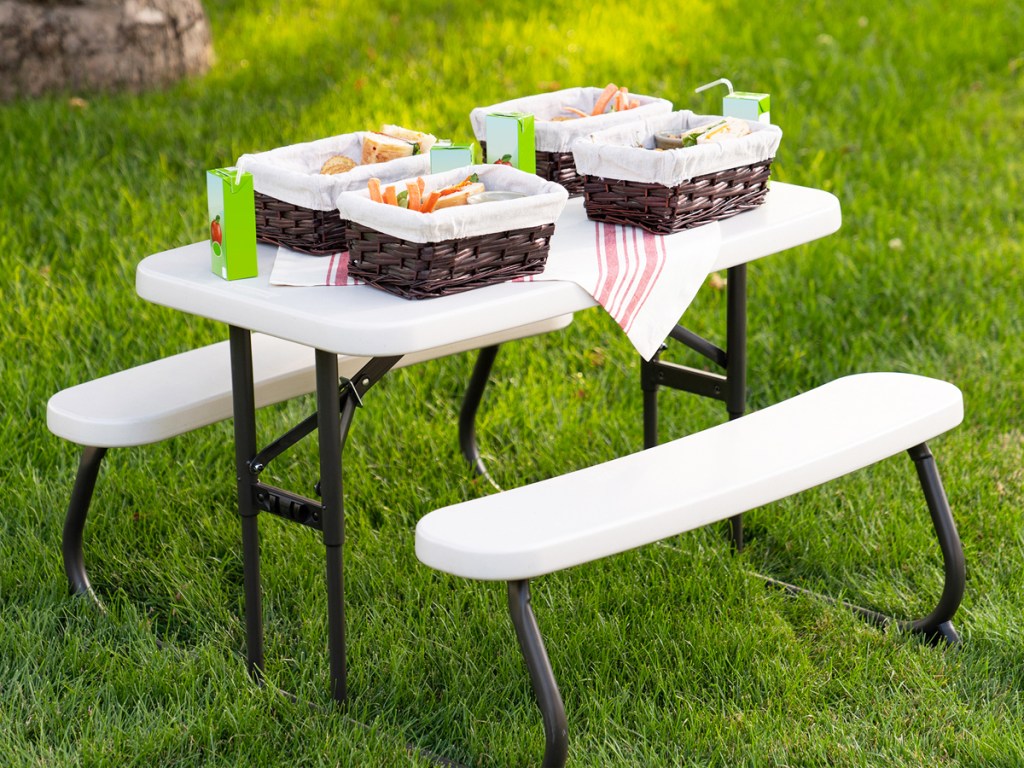 kids table in grass with picnic baskets on top